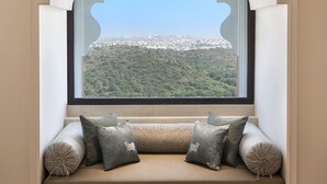 A room with a view of a cityscape through a window with an ornate arch. - Aurika, Udaipur - Luxury by Lemon Tree Hotels (Udaipur)