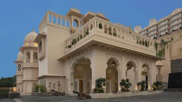 A historic building with ornate architecture, including domes and arches, and a courtyard with a cannon.