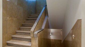 Eine moderne Treppe mit einem Metallgeländer und einer polierten Steinwand.