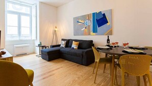 Ein modernes Wohnzimmer mit einer Eckcouch, einem Esstisch mit Stühlen und einem großen, abstrakten Gemälde an der Wand.