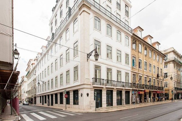 A multi-story building with a classic architectural style, featuring a ground-floor commercial space with shops and a street-level entrance.