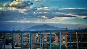 Un quartier résidentiel avec des immeubles d’appartements, une montagne en arrière-plan et un ciel nuageux.