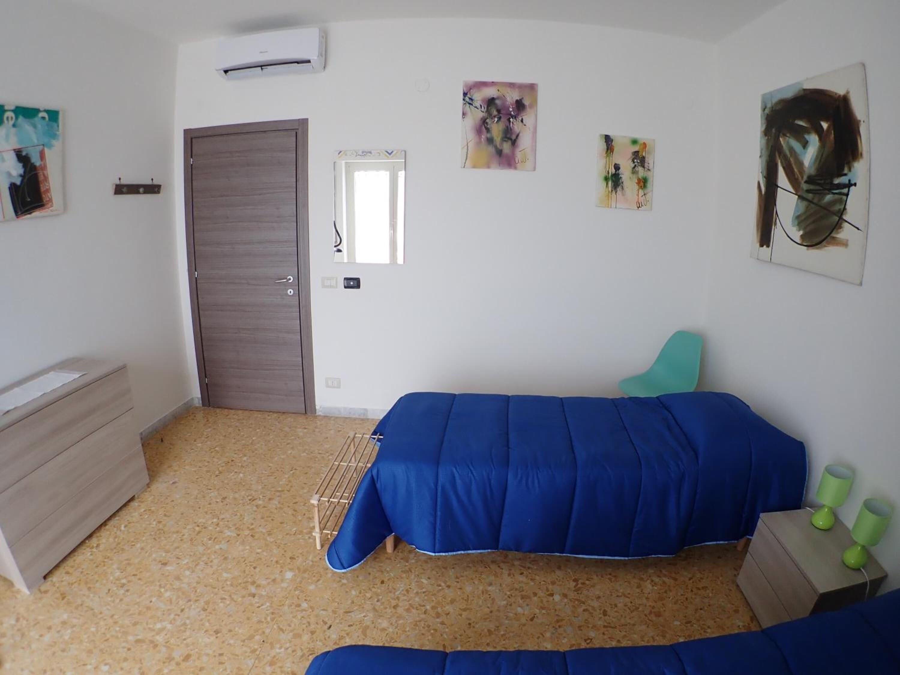 Un dormitorio con dos camas, un armario, un espejo y obras de arte en las paredes.