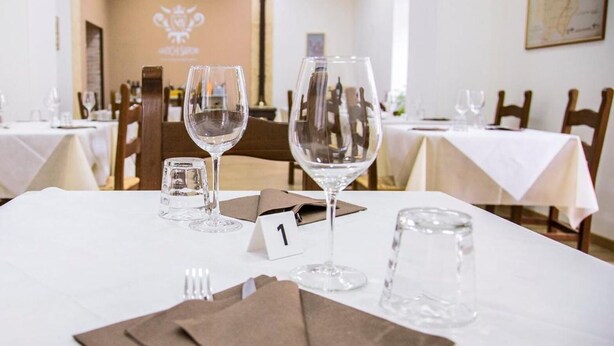 Une table à manger dressée avec des verres à vin, un petit verre, une serviette et un numéro de table.