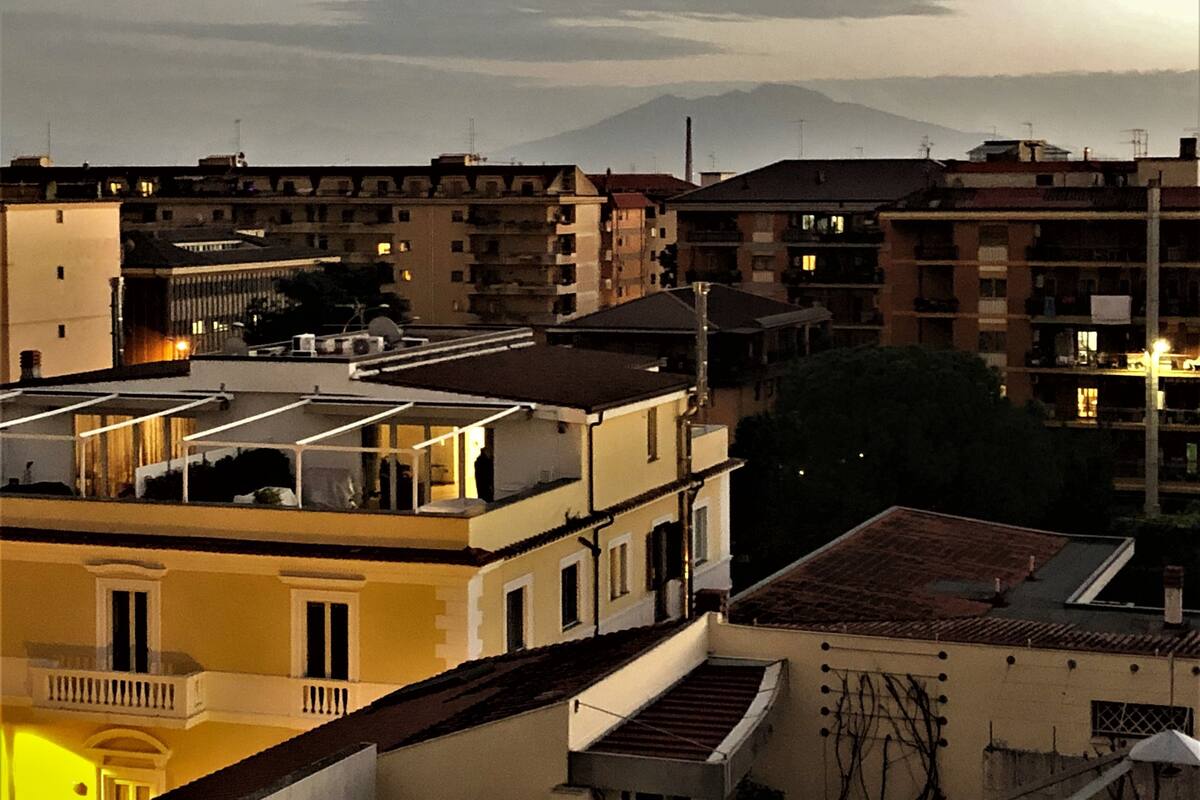 Un edificio residencial de varios pisos con balcones y vistas a montañas distantes.