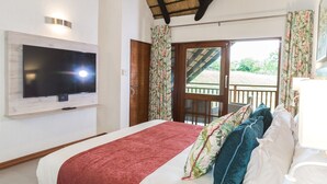 A bedroom with a large bed, a ceiling fan, a TV mounted on the wall, and a balcony with a view of greenery. - Kruger Park Lodge Unit 608B (Mbombela)