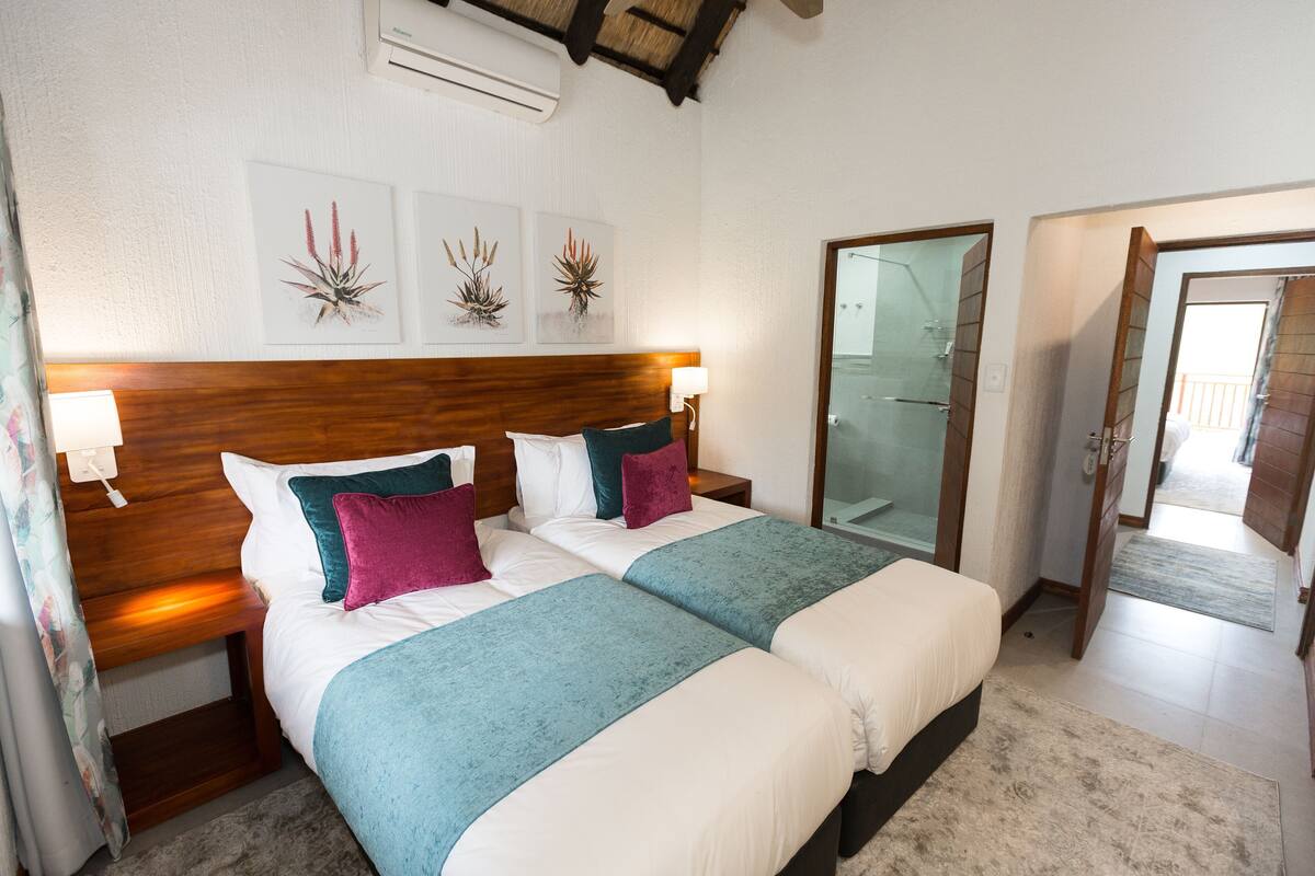 A double bed with a wooden headboard, two bedside tables, and wall-mounted lamps.