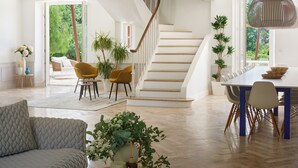 Een ruime woonkamer met een trap, een eettafel met stoelen, en een bank.