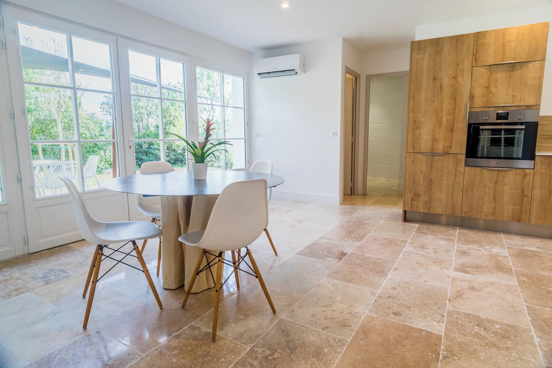 A modern kitchen with a built-in oven and a dining area with a round table and chairs.