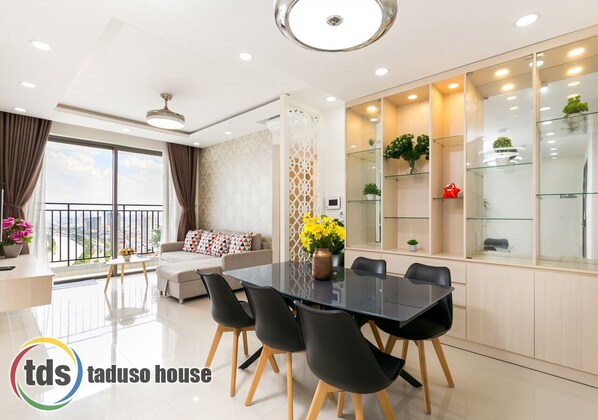 Relax in this stylish living room with a glass dining table, comfortable sofa, and decorative wall panel.