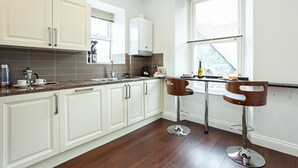 Eine moderne Küche mit weißen Schränken, einer Granitabdeckung und einer Bar mit zwei Hockern.