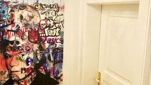 Een gang met een witte deur, een kroonluchter en een muur met kleurrijke graffiti.