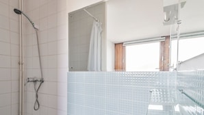 A bathroom with a shower, a bathtub, and a window.