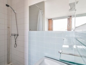 Een badkamer met een douche, een bad en een raam.