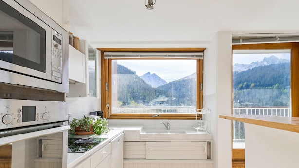 A kitchen with white cabinets, a Bosch microwave, and a window with a mountain view.