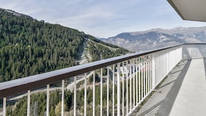 A balcony with a view of a forested valley and distant mountains.