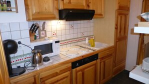 A kitchen with wooden cabinets, a microwave, a stove, and a dishwasher.