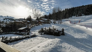 A snow-covered ski resort with wooden cabins and a ski slope.