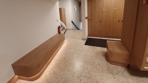Un pasillo con un banco de madera, un extintor y una puerta con panel de madera.