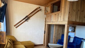A cozy living room with a sofa, a dining table, and blue chairs. - 2* T2 in Courchevel, slope access, parking, valley view, 4 pers. (Courchevel 1850)