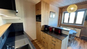 A compact kitchen with wooden cabinets, a black countertop, and a built-in sink. - 2* T2 in Courchevel, slope access, parking, valley view, 4 pers. (Courchevel 1850)