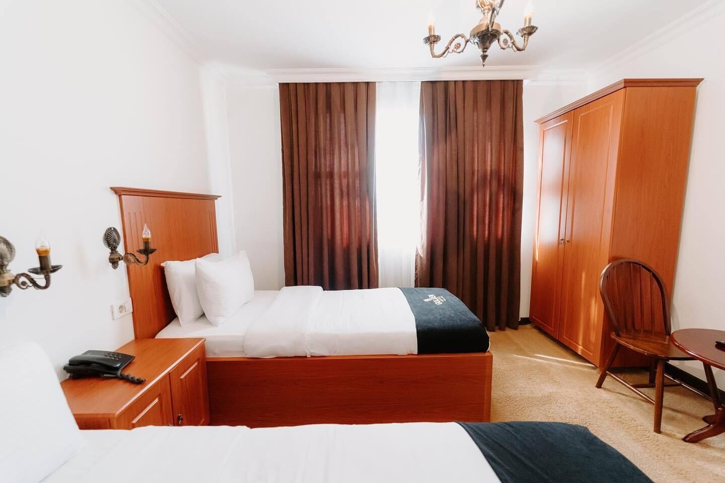 Ett hotellrum med en säng, ett nattduksbord, en lampa, en garderob och en stol.
