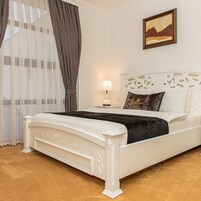 Una cama blanca con un edredón negro, una mesita de noche con una lámpara, y un cuadro en la pared.