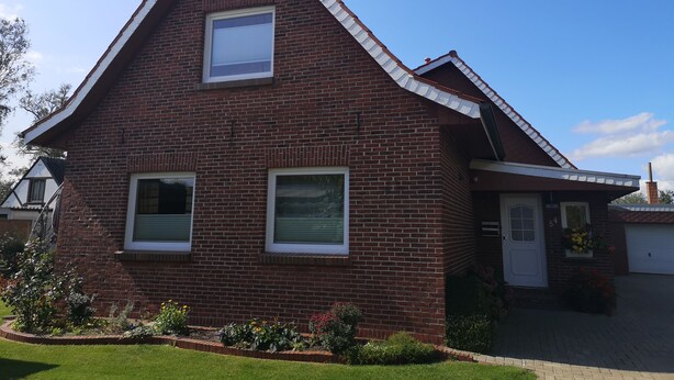 Een tweelaags bakstenen huis met een zadeldak, een voordeur en een garage.