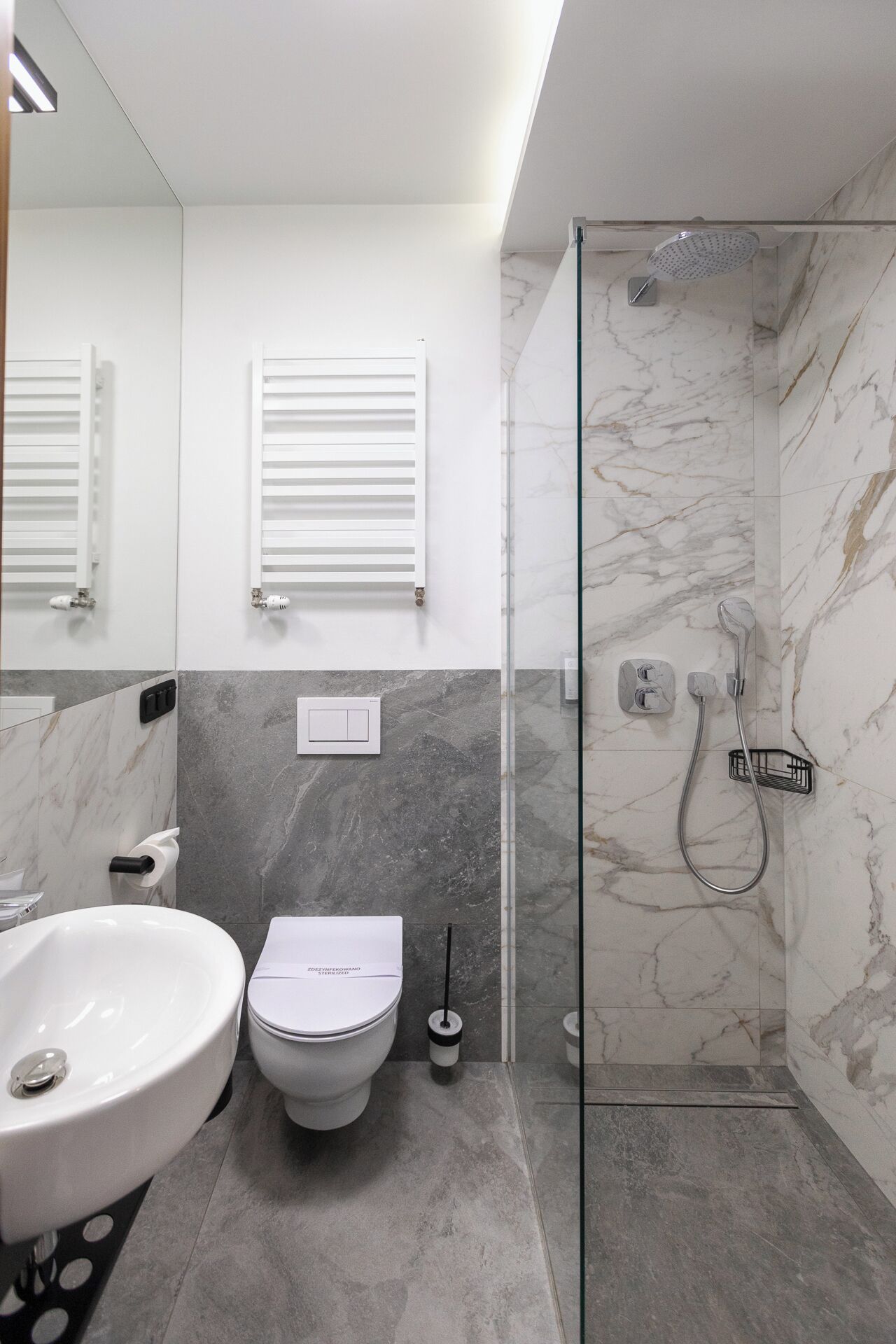 A modern bathroom with a glass-enclosed shower, a white toilet, and a marble-tiled sink.