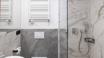 A modern bathroom with a glass-enclosed shower, a white toilet, and a marble-tiled sink.