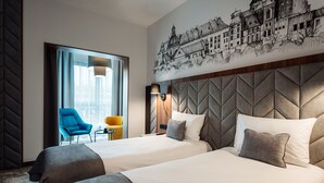 A hotel room with two beds, a cityscape mural, a modern chair, and a lamp. - Focus Hotel Premium Kraków (Kraków)