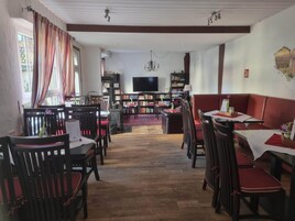 A cozy restaurant with wooden furniture, a fireplace, and a bookshelf.