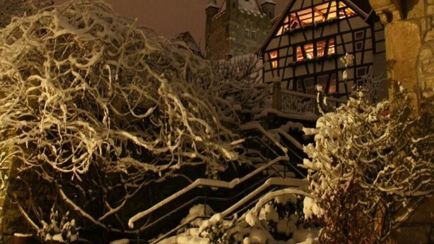 A snow-covered outdoor area with a building featuring a traditional architectural style, including a tower with a spire. - Hotel Herberge zur Traube (Bad Wimpfen)