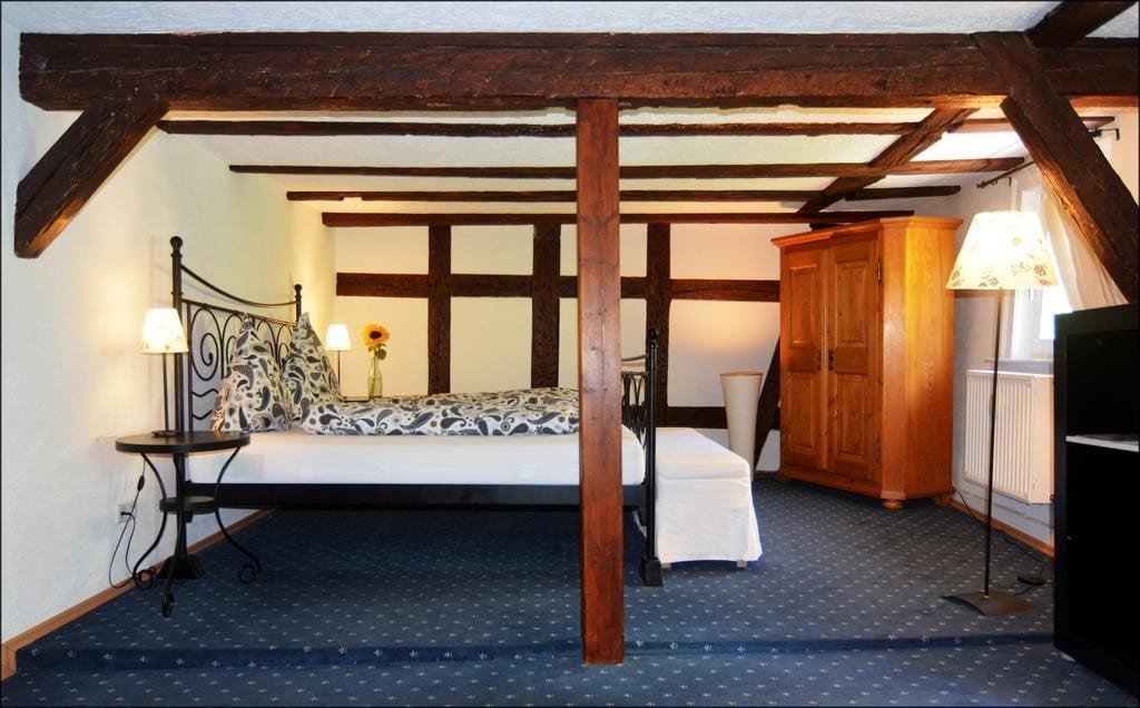 Un dormitorio con cama, mesitas de noche, un armario de madera y una lámpara.