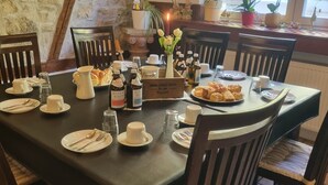 A dining table set with plates, cutlery, and bottles, surrounded by chairs in a room with stone walls and a window. - Hotel Herberge zur Traube (Bad Wimpfen)
