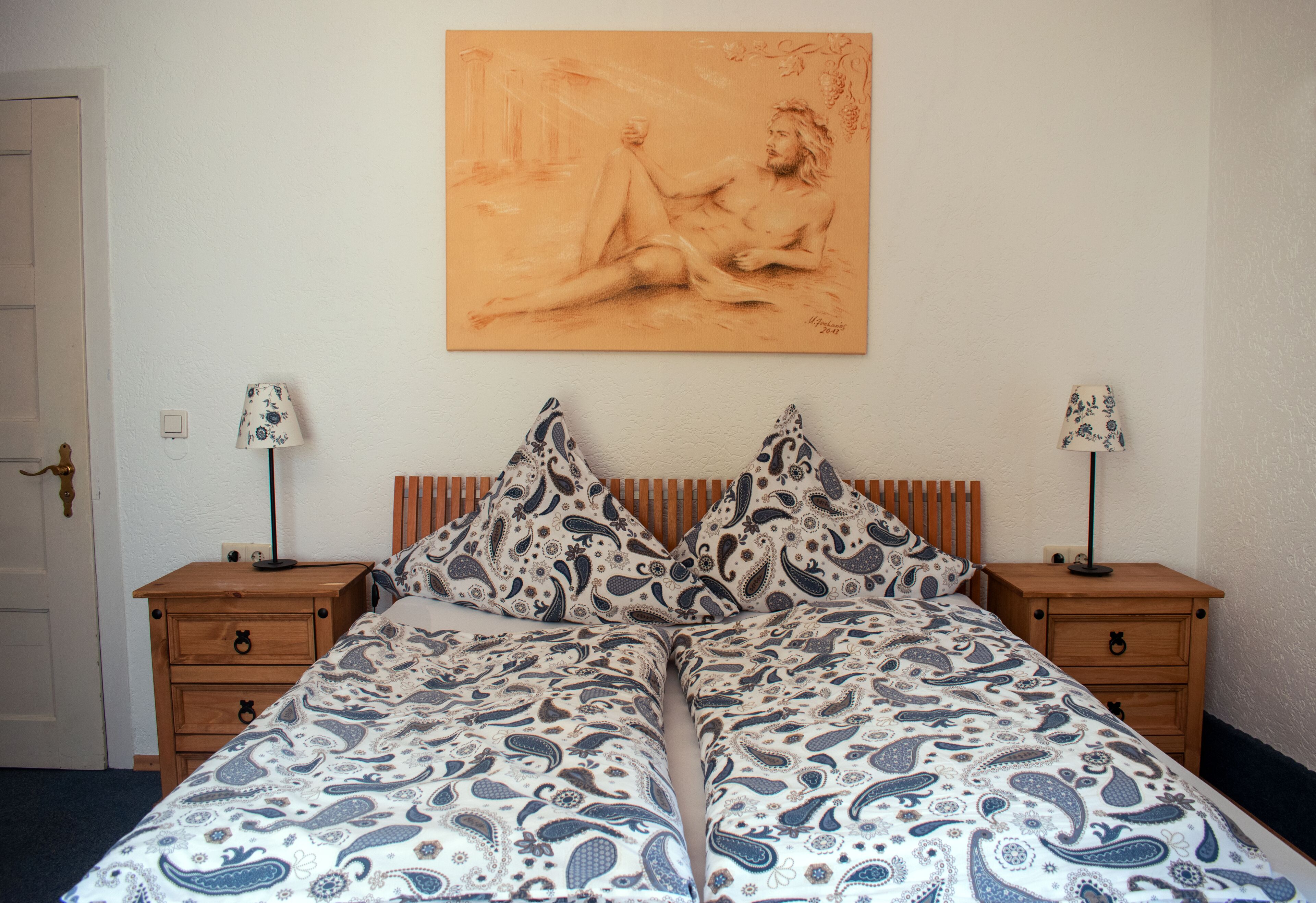Ein Schlafzimmer mit einem Bett, zwei Nachttischen und einem Wandbild.