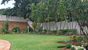 A well-maintained garden with a variety of plants and a paved pathway. - The Grand Orchid Guesthouse (Durban North)