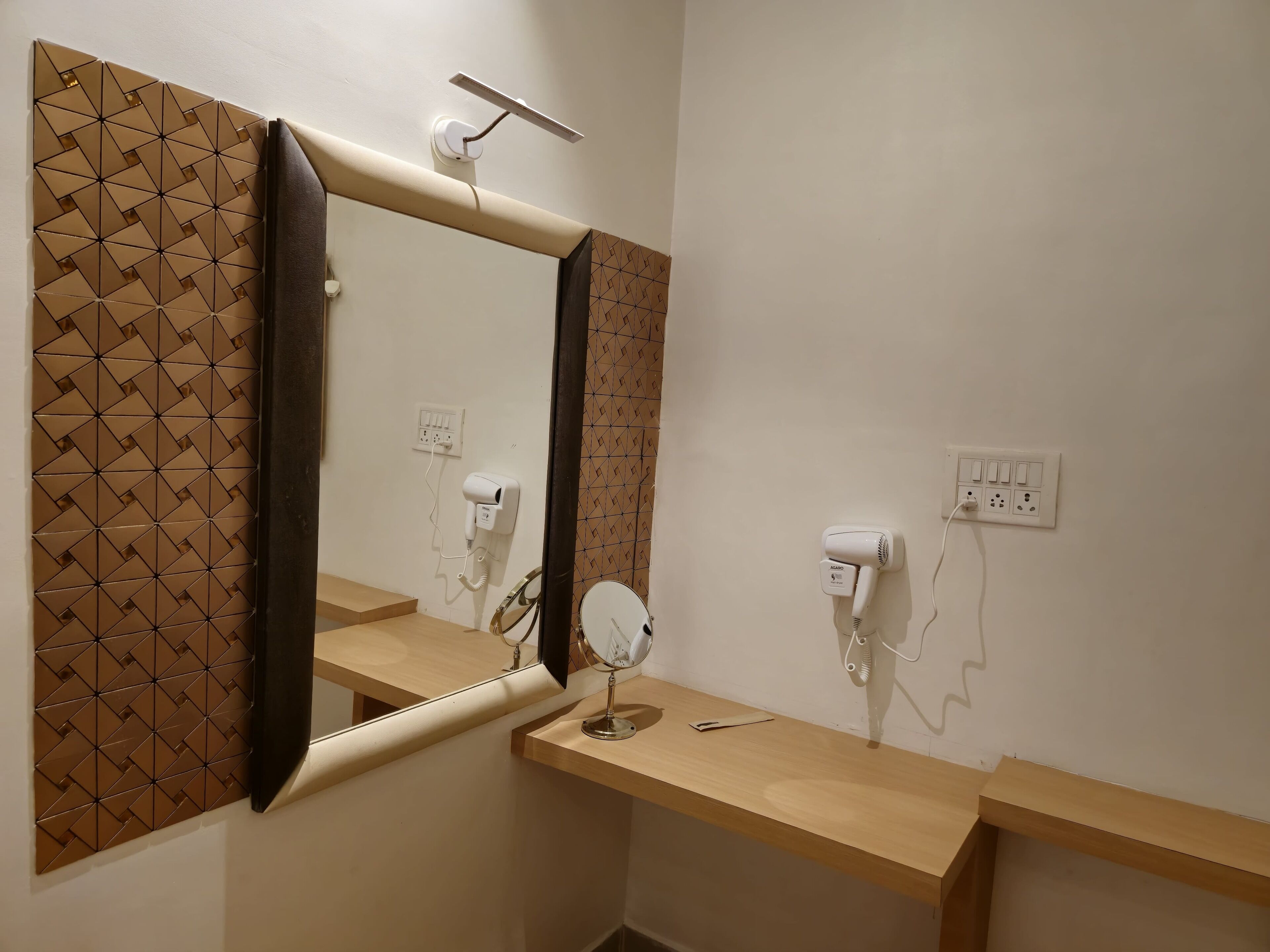 Une salle de bain équipée d’un miroir, de deux sèche-cheveux, d’une coiffeuse avec miroir et d’un porte-serviettes.