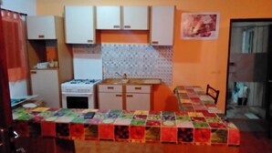 A compact kitchen with white cabinets, a gas stove, and a tiled backsplash. - Rental Studio Floor Villa (Abidjan)