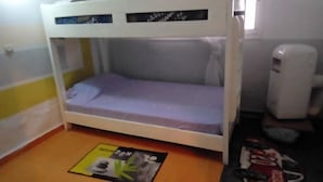A bunk bed with a mattress and pillows, a small table with a magazine, and a white heater on the floor. - Rental Studio Floor Villa (Abidjan)