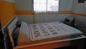 A room with a bed, a window with bars, a radiator, and a telephone. - Rental Studio Floor Villa (Abidjan)
