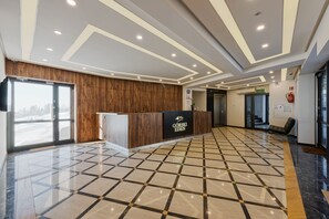 Ein Hotel-Empfangsbereich mit Holzbude, Fliesenboden und einem modernen Deckenstil.