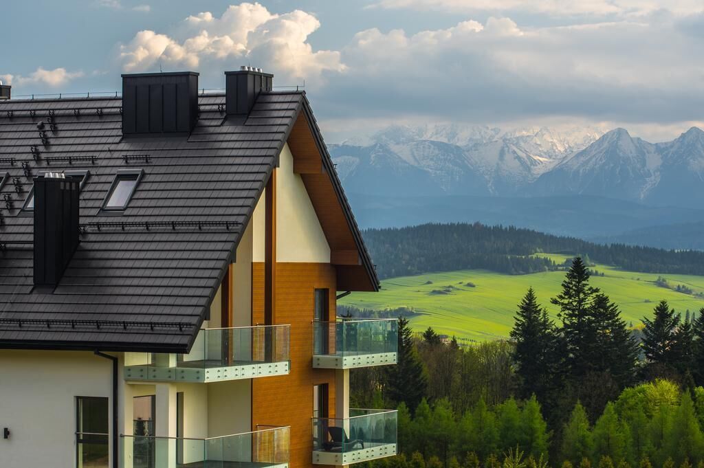 A modern two-story house with a sloped roof, large windows, and a balcony.