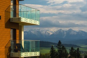 Een modern gebouw met een glazen balkon met uitzicht op een bergachtig landschap.