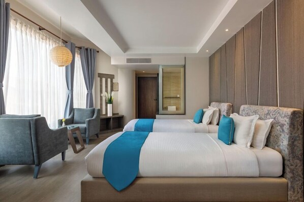 A modern hotel room with a large bed, two armchairs, a desk, and a large window with curtains. - Kathmandu Guest House by KGH Group (Kathmandu)