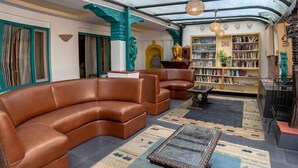 A spacious lounge with leather sofas, a glass coffee table, and a bookshelf filled with books. - Kathmandu Guest House by KGH Group (Kathmandu)