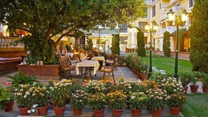 An outdoor patio with tables and chairs, surrounded by potted plants and a well-maintained lawn. - Kathmandu Guest House by KGH Group (Kathmandu)