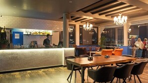 A modern bar area with a counter, bar stools, and a seating area with tables and chairs. - Kathmandu Guest House by KGH Group (Kathmandu)