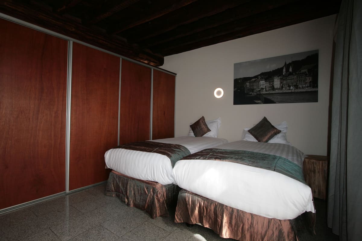 Een kamer met een bed, een houten garderobe en een ingelijst schilderij aan de muur.