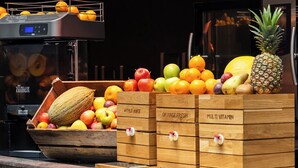 A fruit display with wooden crates labeled 'APPLE JUICE,' 'ORANGE FRESH,' and 'MULTI VITAMIN.' - Amosa Liège City Centre Apart Regence 10 (Liege)